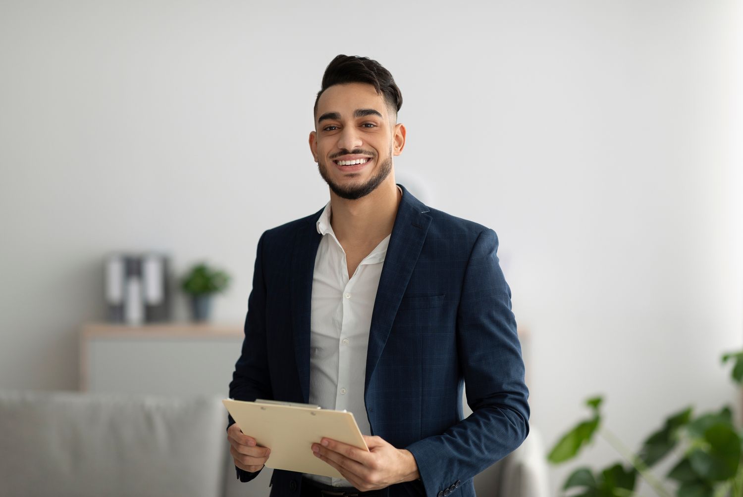 Friendly middle eastern male psychologist smiling at camera during therapy session, working in clinic, free space. Happy psychotherapist posing at office